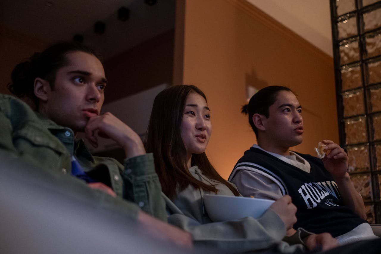 Three friends watching TV and eating snacks